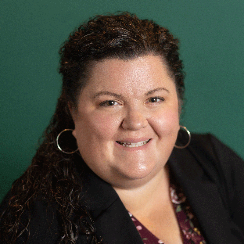 A portrait of Darla Cazares, looking at the camera, against a deep green background
