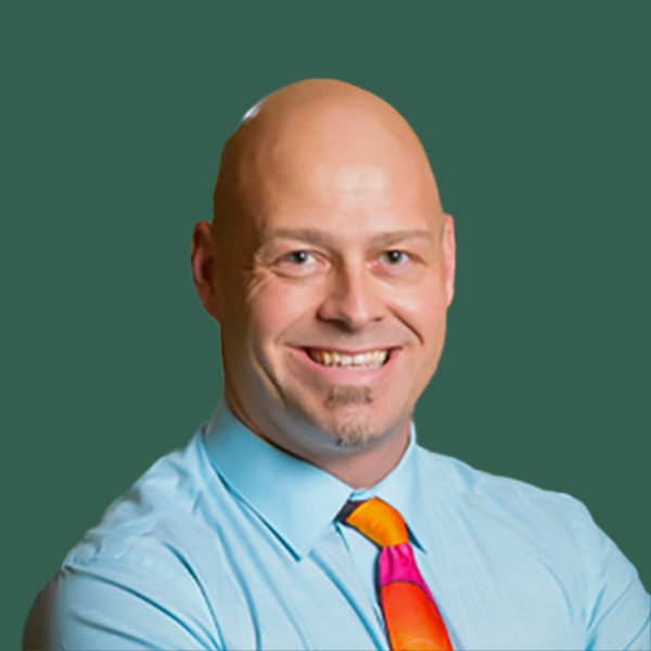 Portrait of Jesse Kinney against a green background, looking at the camera and smiling