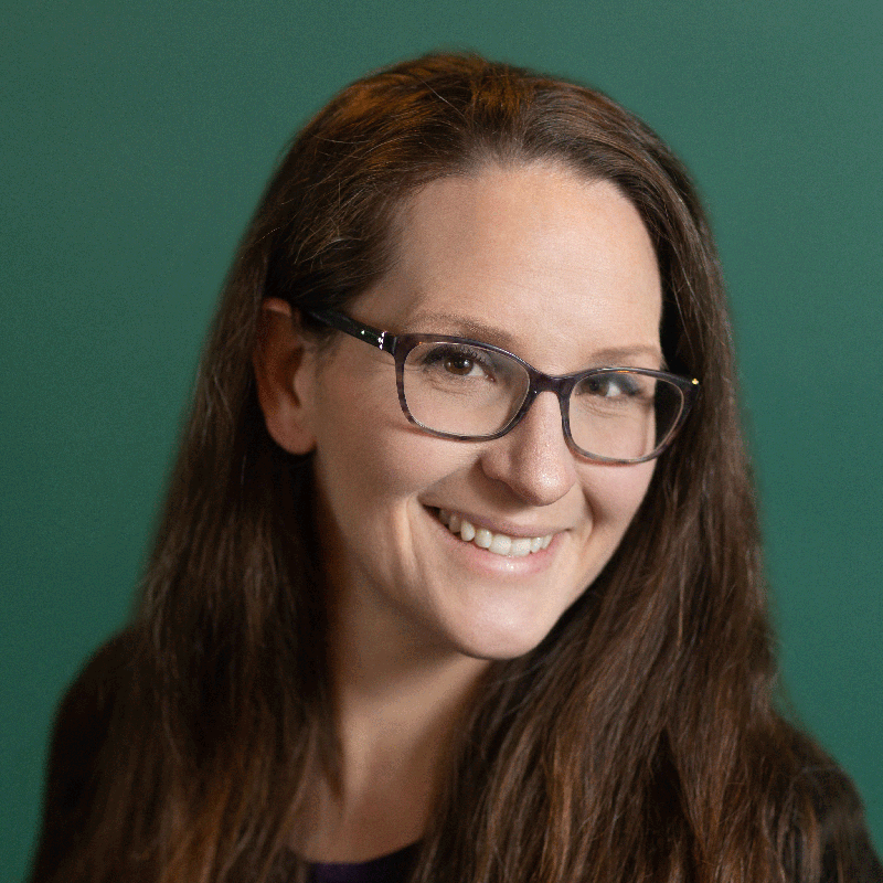 A portrait of Rachel O'Neil, looking at the camera, against a deep green background