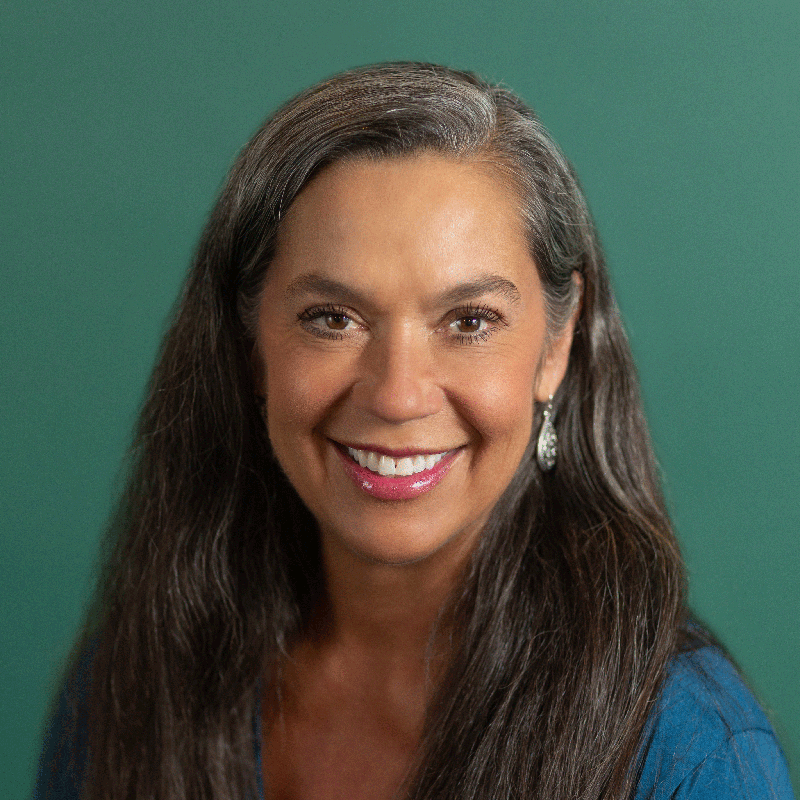 A portrait of Robin Cox, looking at the camera, against a deep green background